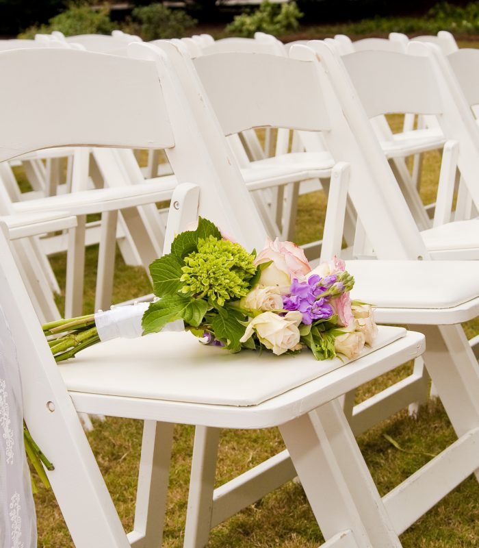 White Folding Chairs at an Outdoor Wedding with flowers